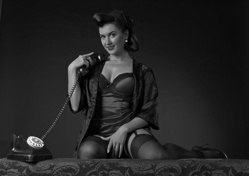 Beautiful woman in pin up style with perfect hair and make up speaking via vintage phone.