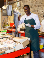 Fish shop worker near showcase with raw seafood