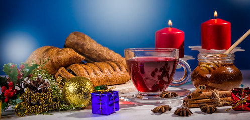 Traditional Christmas apple punch with cinnamon and honey on a table of candles on a light background