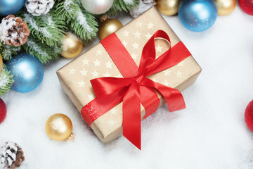christmas gift box with balls and fir-tree brunch on snow