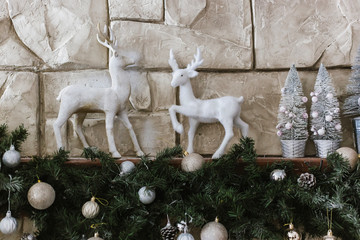 Christmas figures of deer are on the shelf by the fireplace