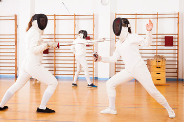 female athletes practicing  movements at fencing battle