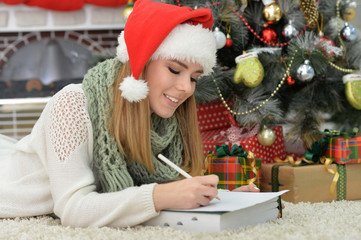 Fototapeta na wymiar Smiling girl in Santa hat writing letter