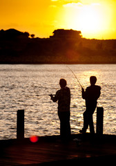 Silhouette of two friends fishing