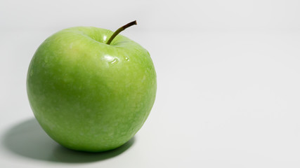 Green apple on white background with space to right.