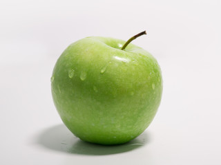 Green apple with water drops on white background. Side view.