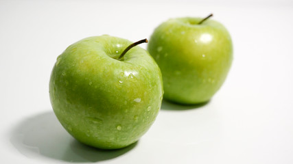 Green apples with water droplets on white background