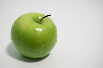Green apple with water droplets on white background, space on right