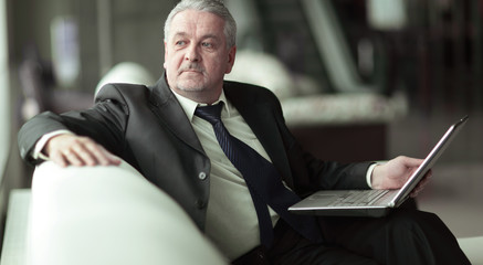 pensive businessman with laptop sitting in office lobby