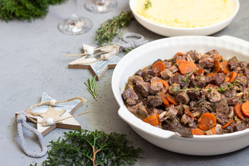 Beef bourguignon or meat stew with vegetables and herbs in a casserole.