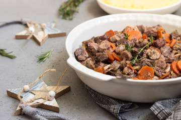 Beef bourguignon or meat stew with vegetables and herbs in a casserole.