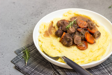 Beef bourguignon or meat stew with vegetables and herbs in a casserole.
