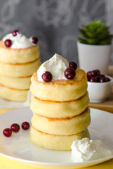Cottage cheese pancakes with sour cream and berries on yellow background. Syrniki. Russian food. Copy space