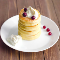Cottage cheese pancakes with sour cream and berries on rustic background. Syrniki. Russian food. Copy space