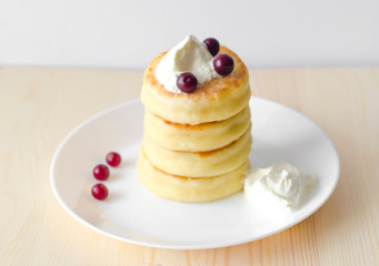 Cottage cheese pancakes with sour cream and berries on rustic background. Syrniki. Russian food. Copy space