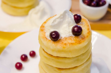 Cottage cheese pancakes with sour cream and berries on yellow background. Syrniki. Russian food. Copy space
