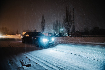 Car at night at snowe road with a lot of snowing outside