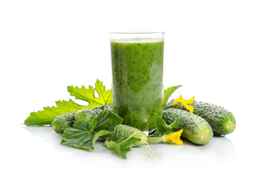  glass with green smoothie and  cucumbers, flowers, leaves isolated on white