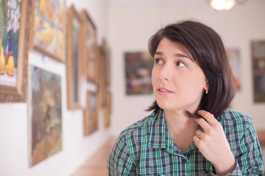A young beautiful woman looking at painting.