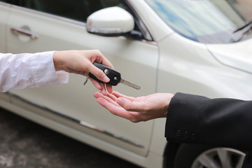 Car salesman handing over the keys for a new car to young businessman.