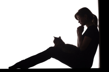 silhouette of a woman sitting on the floor in a corner on a white isolated background with a cat