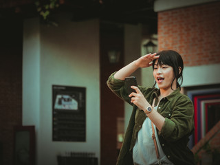 Asian woman using smartphone with happy mood in shopping mall