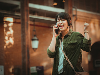 Asian woman using smartphone with happy mood in shopping mall