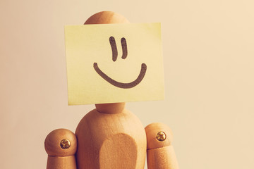 Concept face of a happy person. Wooden mannequin with a sticker on his face with the image of...