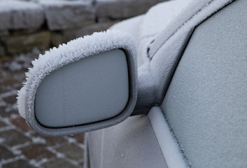 Car wing mirror covered up with ice crystal when temperature going down in winter season