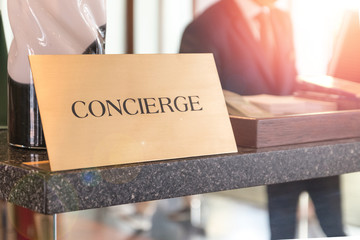 Concierge service desk counter with happy employee staff receptionist working in front of hotel with tourist guest business customer. - obrazy, fototapety, plakaty
