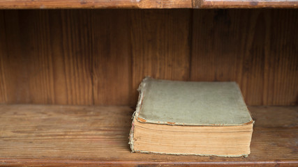 Antique closed book on a wooden shelf