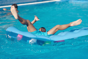 Cute European boy is diving from the inflatable blue floater into the hotel’s swimming pool. He is enjoying his summer vacations. - 236785104