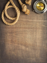 ship compass and rope at wooden background