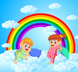 Two happy children is fighting a pillows with rainbow scenery 