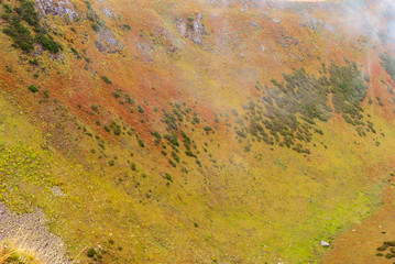 background, landscape - mountainside with colorful vegetation, autumn high altitude grassland, visible through the clouds