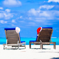 Christmas concept: beach loungers with red Santa and straw hats background beautiful turquoise sea 