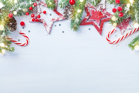 Merry Christmas holiday card or banner with snowy fir branches, red stars and festive decorations. Magic bokeh lights.