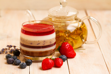 Italian dessert - panna cotta with berries and herbal lavender tea. Homemade berries aspic with different layers of chocolate, milk, cream, berry with fresh strawberries and blueberries