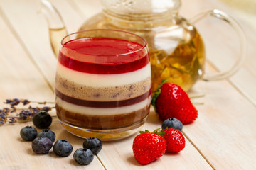 Italian dessert - panna cotta with berries and herbal lavender tea. Homemade berries aspic with different layers of chocolate, milk, cream, berry