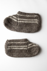 pair of hand knitted woolen slippers isolated on white background