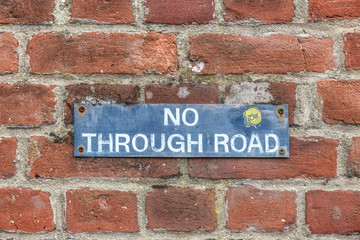 Brick wall with No through road sign