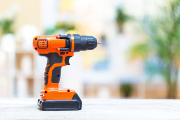 Cordless electric drill on a bright interior room background
