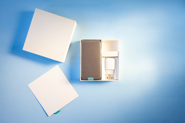 open box with new smart phone on blue background