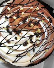 close up of a delicious chocolate cake with black and white chocolate pieces and syrup