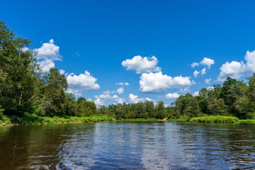 water stream in river of Amata in Latvia with sandstone cliffs, green foliage