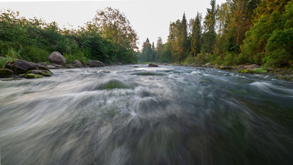 water stream in river of Amata in Latvia with sandstone cliffs, green foliage