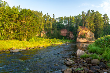water stream in river of Amata in Latvia with sandstone cliffs, green foliage