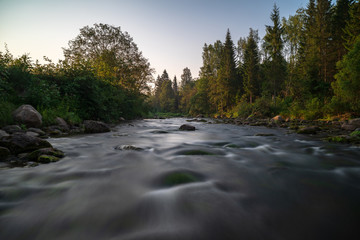 water stream in river of Amata in Latvia with sandstone cliffs, green foliage