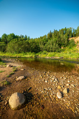 water stream in river of Amata in Latvia with sandstone cliffs, green foliage