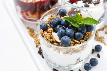 sweet desserts with fresh berries in glasses on white table, closeup